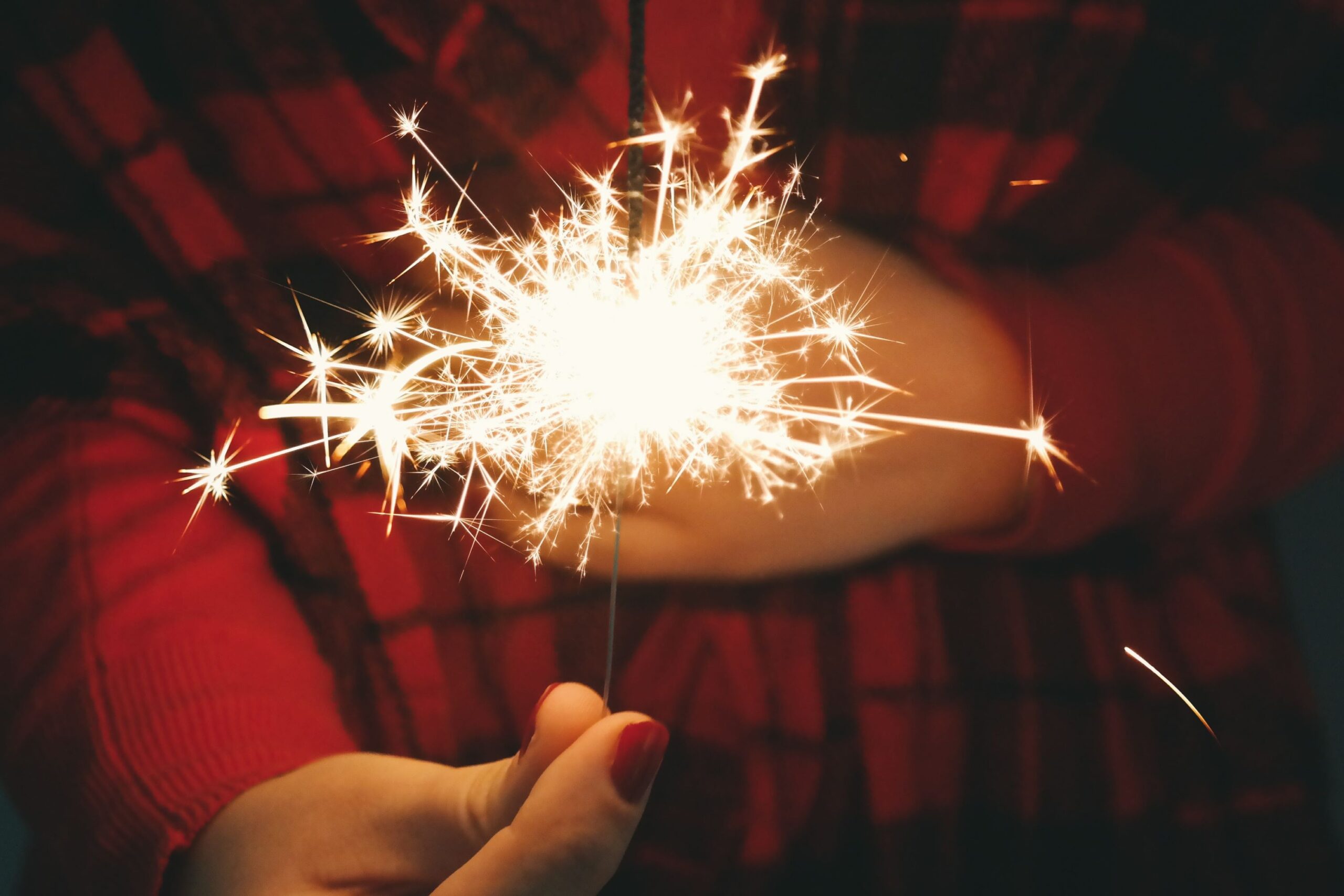 hand with painted nails holds lit sparkler