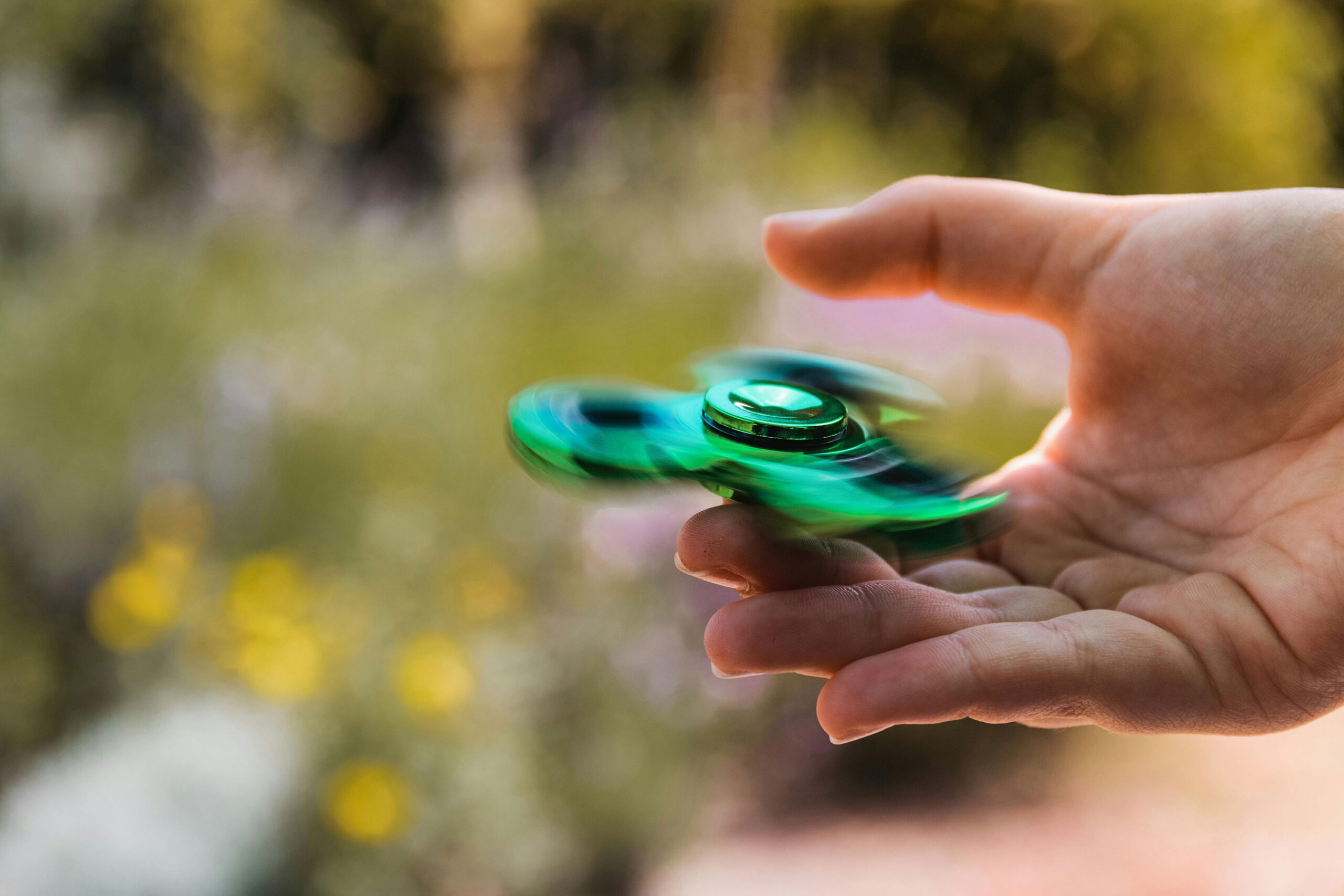 hand holds green fidget spinner which is spinning