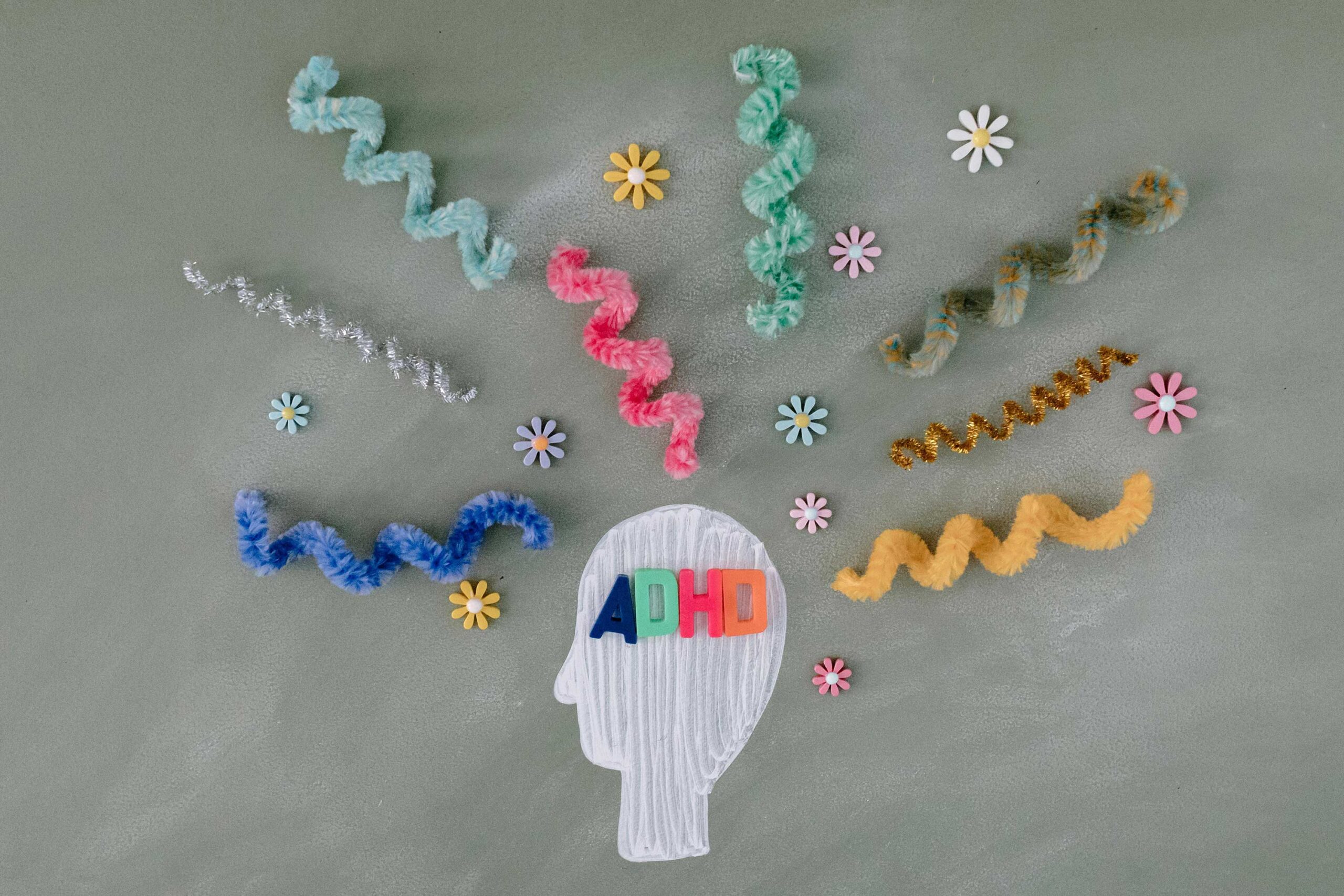 head with "ADHD" on it surrounded by swirly pipe cleaners and flowers